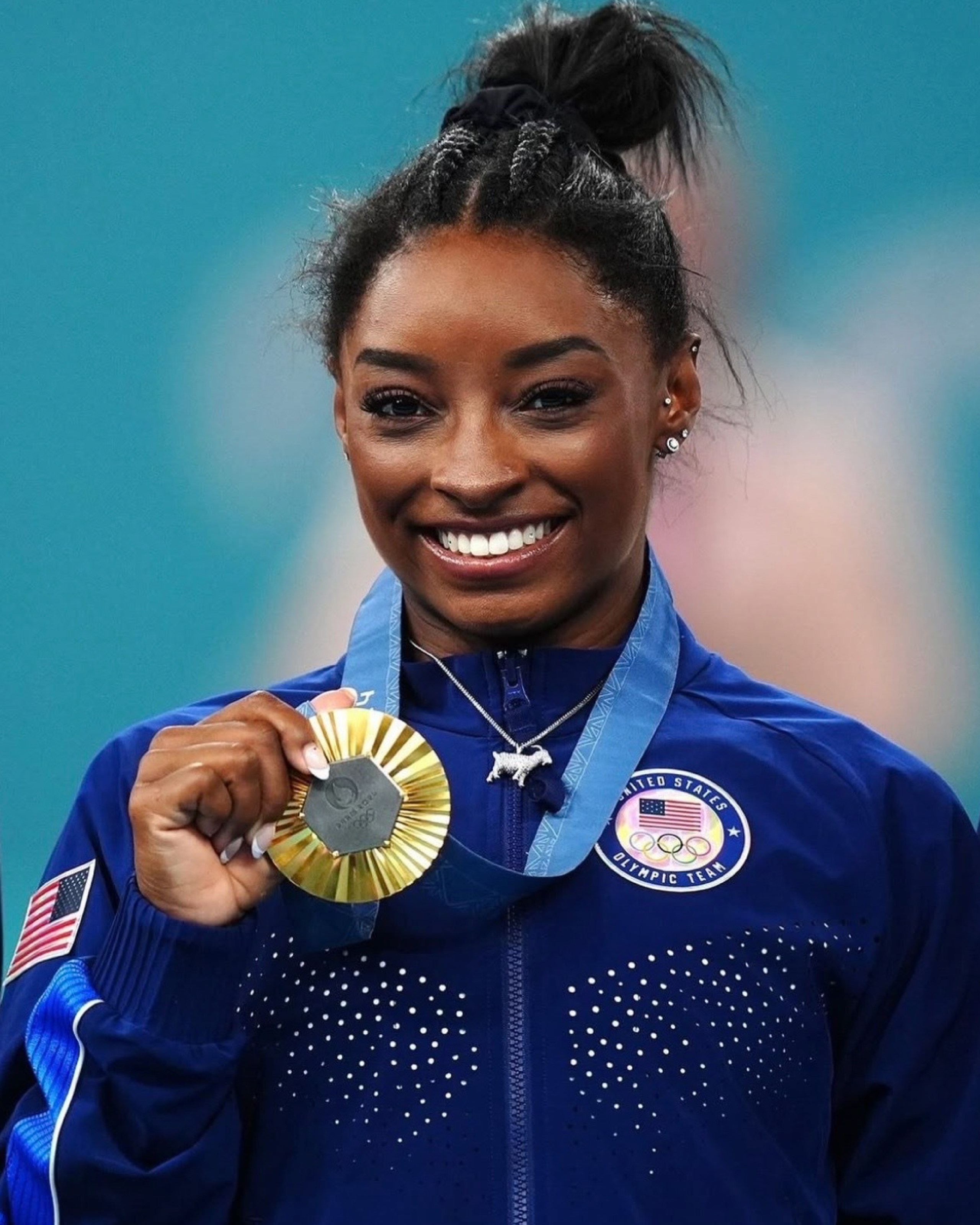 Simone Biles wears a diamond-studded GOAT pendant after winning Olympic gold