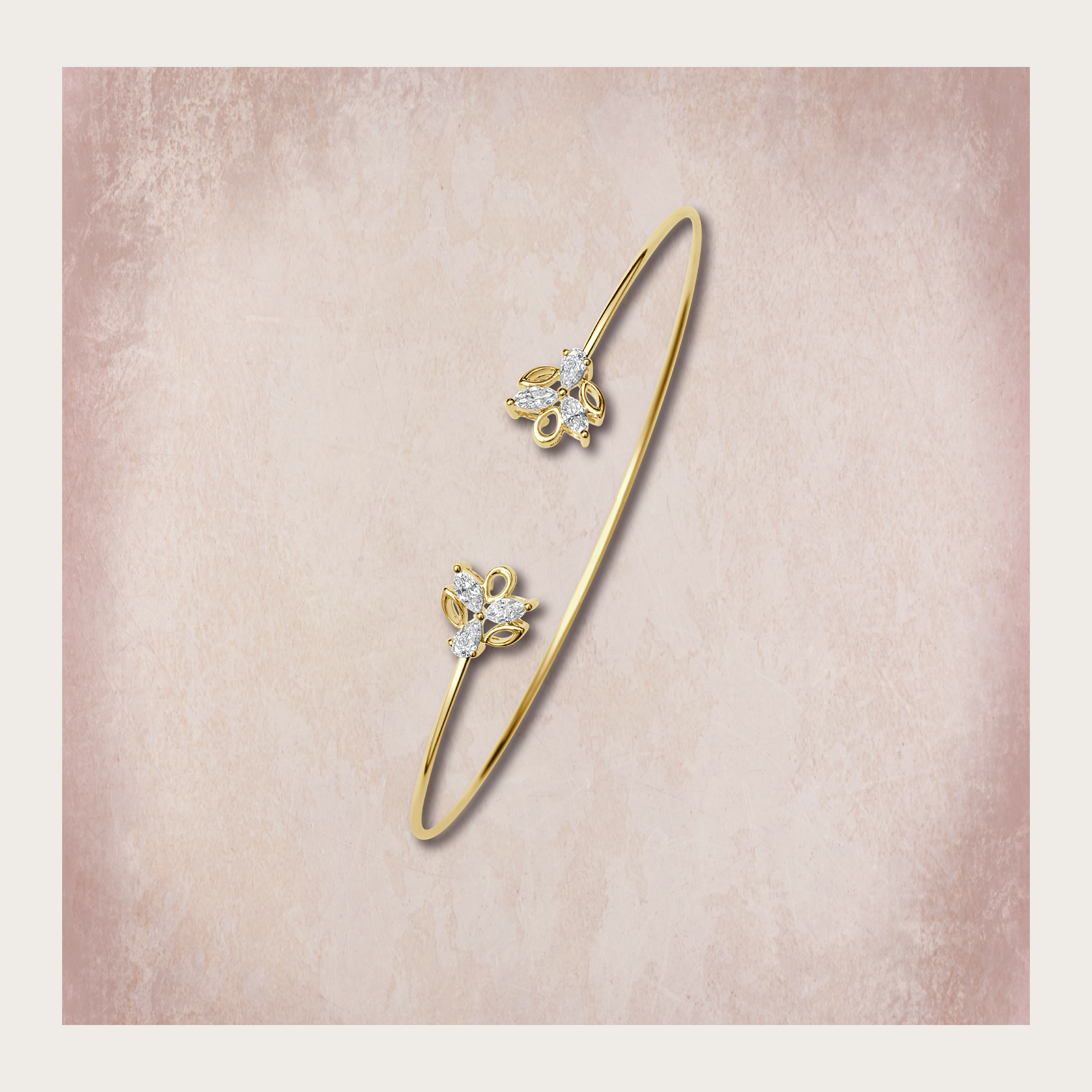Delicate yellow gold open bangle bracelet featuring twin floral diamond motifs