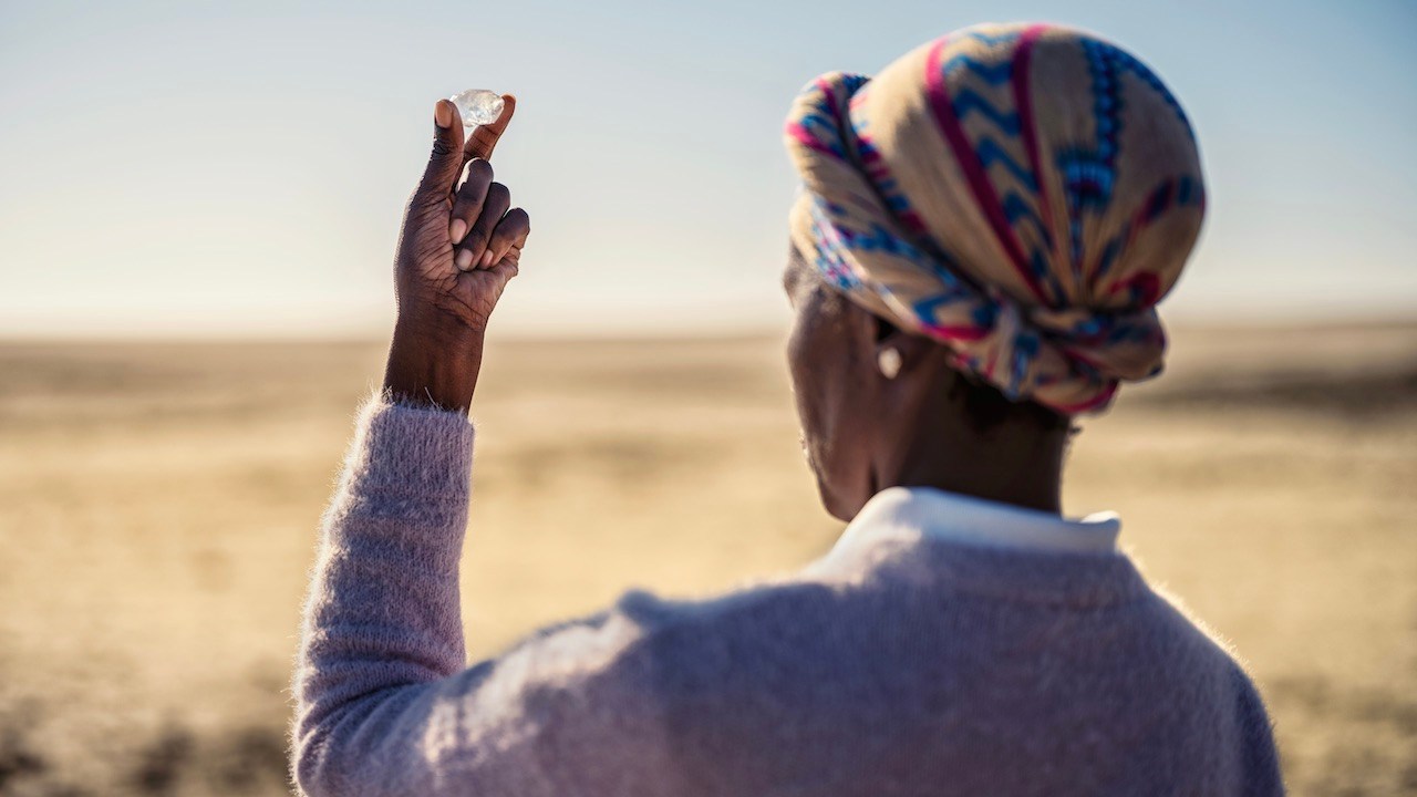Woman holding a rough diamond in Botswana from the 2025 Jared film by director Luc Jacquet, A Diamond is Born.