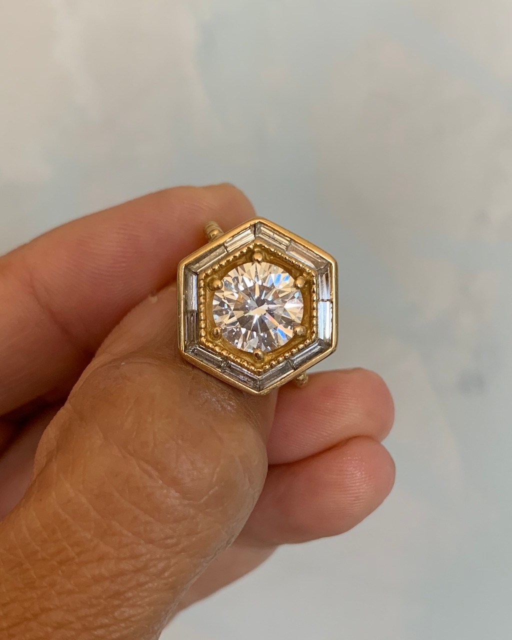 In the second reimagining of her diamond, Lauren Harwell Godfrey reset her round diamond in 18-karat yellow gold with a hexagonal halo of baguette-cut diamonds. ((Courtesy of the Designer)