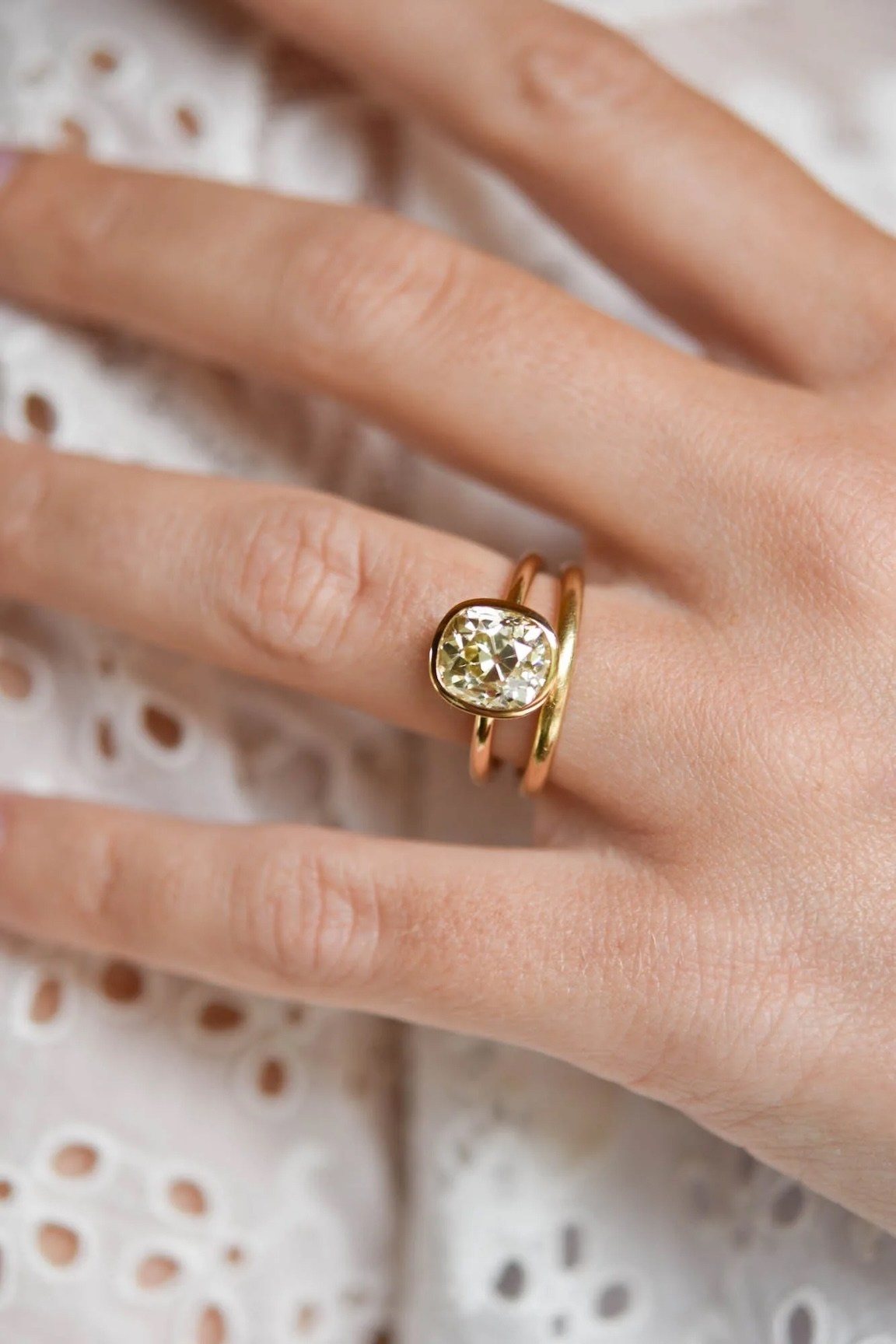 Old mine-cut diamond in a yellow gold bezel set solitaire engagement ring