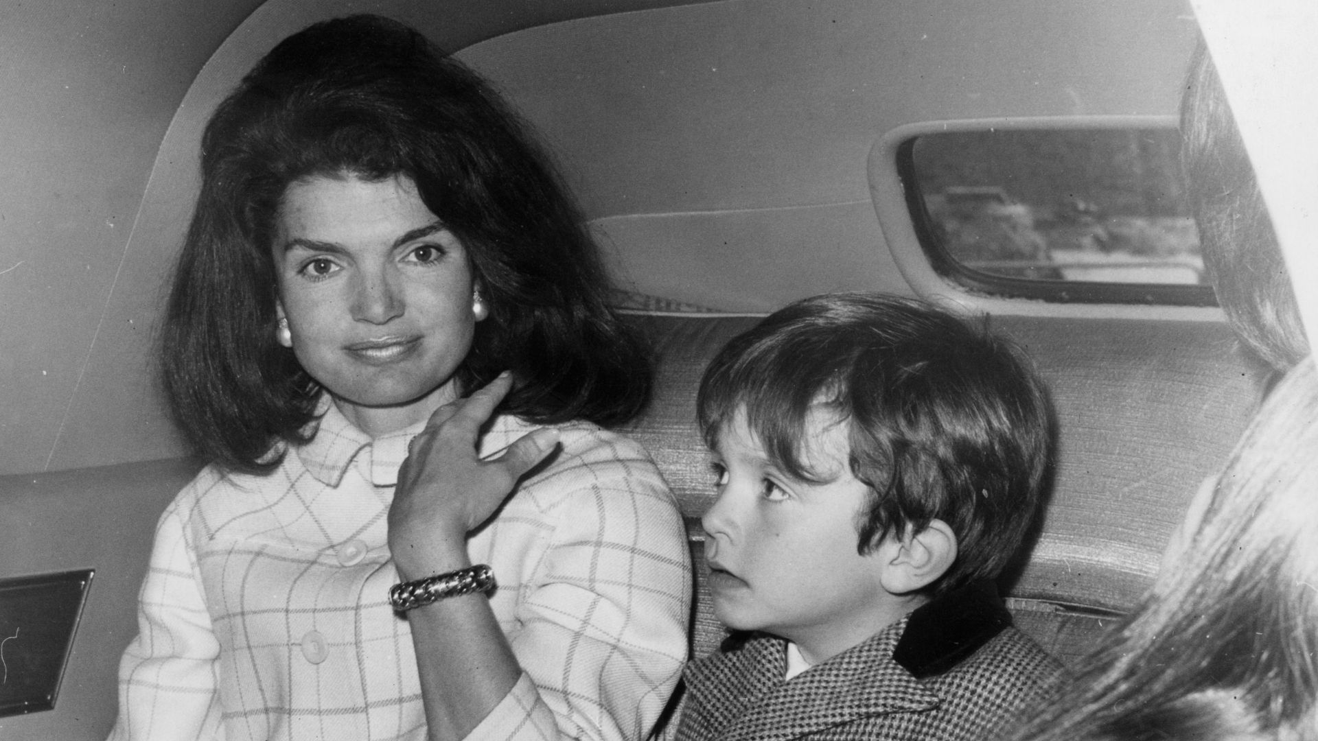 Jackie Kennedy Onassis in a car with one of her nephews (son of her sister, Princess Radziwill). She is stopping over in London on her way home after a visit to Spain. (Photo by Roger Jackson/Getty Images)