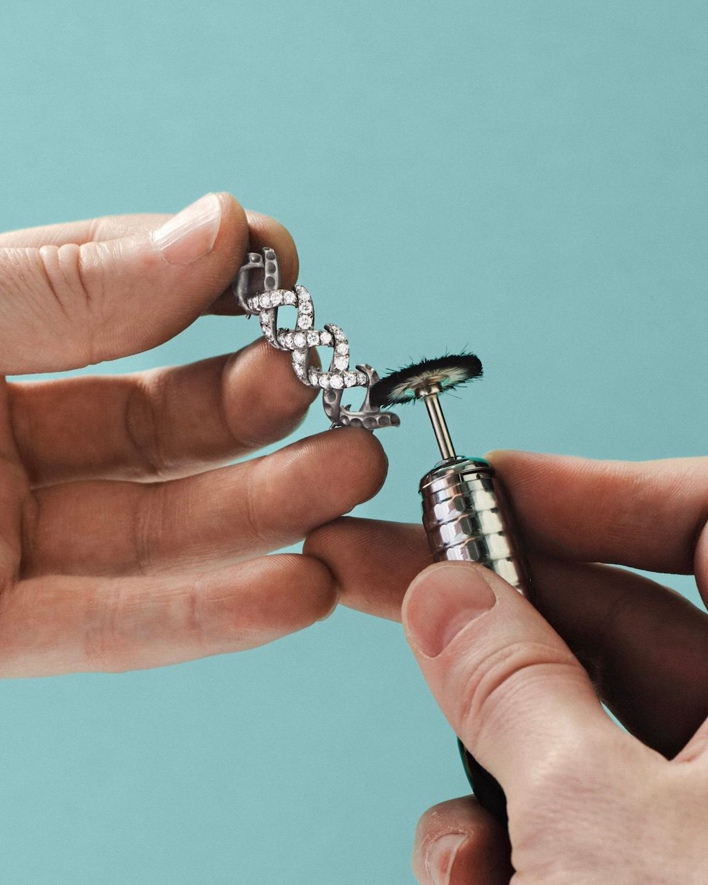 Handcrafting the Diamond Jasmine necklace from Blue Book 2026: Hidden Garden. An artisan carefully polishes a partially set necklace component.