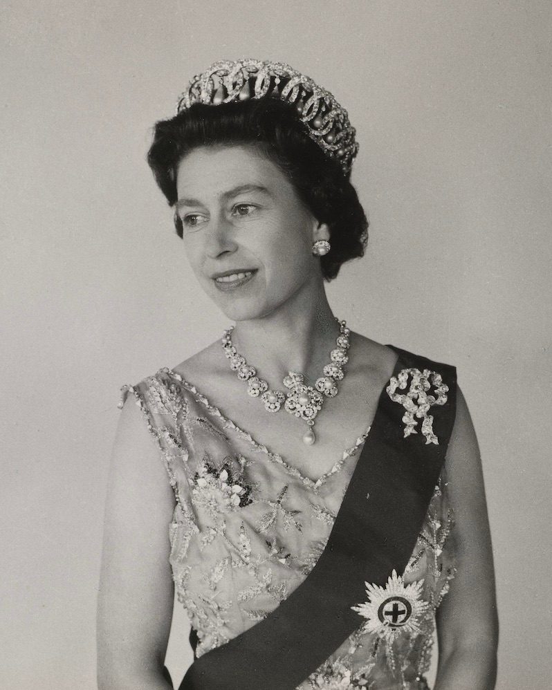 Queen Elizabeth II wears a sash featuring Queen Mary's Diamond Lover’s Knot Bow Brooch and the Star of the Order of the Garter, photographed by Cecil Beaton in 1968. (Courtesy of Royal Collection Trust)